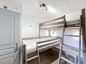 A bunk bed room with a door, a light fixture, and a wall decoration.