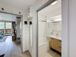 Un baño moderno con cabina de ducha de vidrio, tocador de madera y un espejo grande.