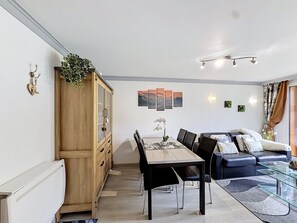 Una sala moderna con comedor, un sofá, una mesa de centro de vidrio y un mueble.