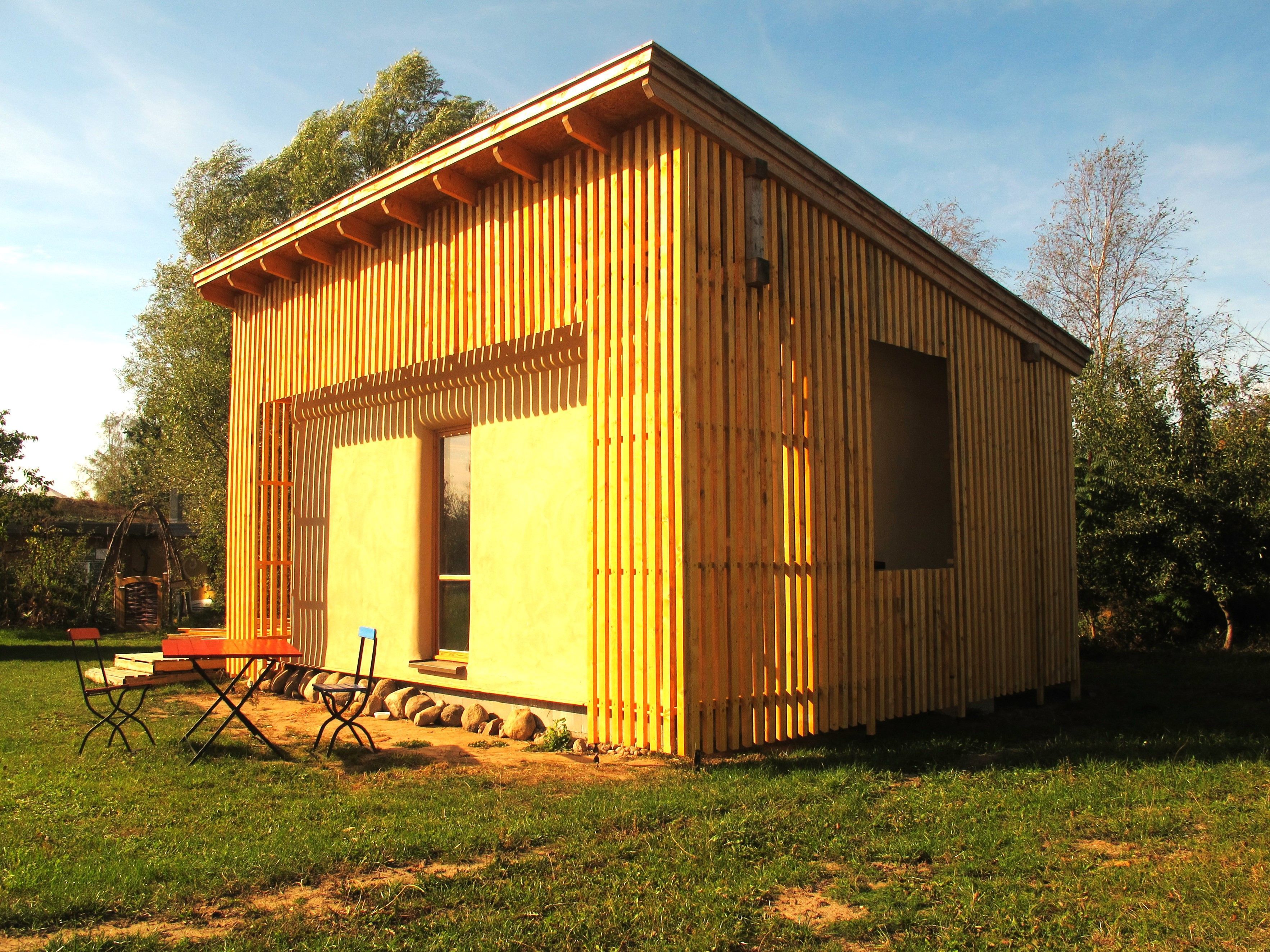 Un edificio de madera con techo plano, ventanas grandes y una puerta.