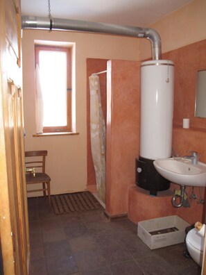 Een badkamer met een raam, douche, wastafel en toilet.