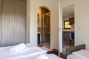 Un dormitorio con cama, armario y puerta abierta que da a un baño con ducha.