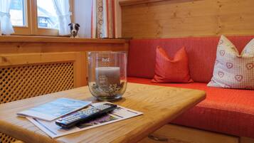 Een houten tafel met een afstandsbediening, documenten en een kaars in een glazen houder.