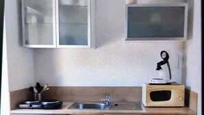 A compact kitchen with a washing machine, a sink, and a microwave.