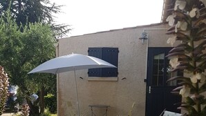 A small house with a garden, a patio umbrella, and outdoor furniture.