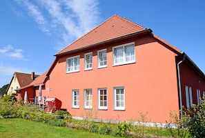 Punainen, kaksikerroksinen talo, jossa on valkoiset ikkunakehykset ja punainen katto.