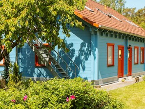 A blue house with a red roof, a visible staircase, and a small garden with pink flowers. - Double room 4 - Rankwitzer Hof (Rankwitz)