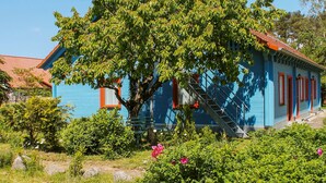A blue house with a red roof, surrounded by lush greenery and a tree with a ladder. - Double room 4 - Rankwitzer Hof (Rankwitz)