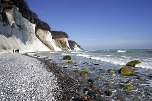 Ein felsiger Strand mit weißen Klippen und brechenden Wellen.
