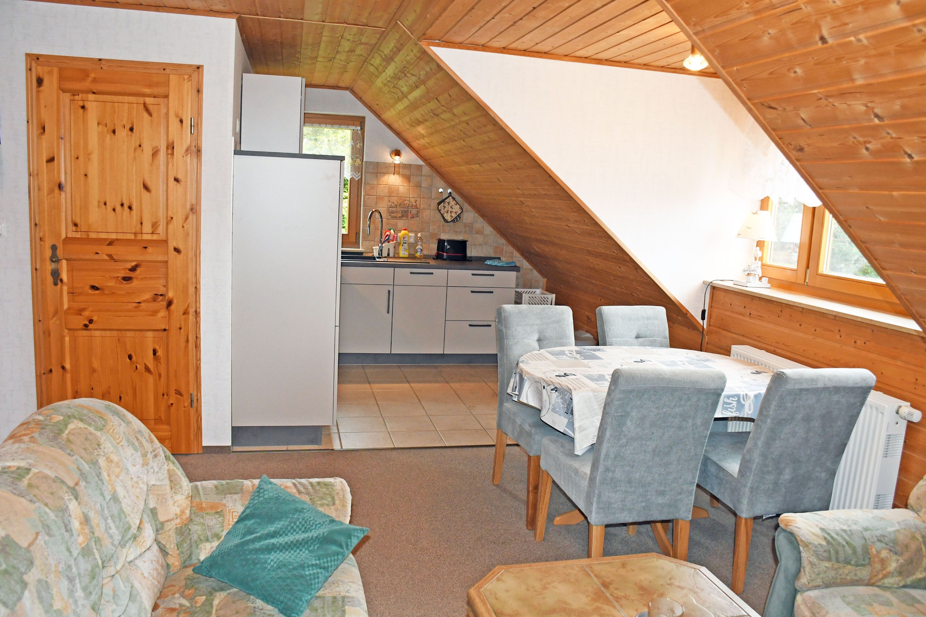 Een knus loft-appartement met een eethoek, een kitchenette en een houten deur.