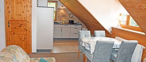 Een knus loft-appartement met een eethoek, een kitchenette en een houten deur.