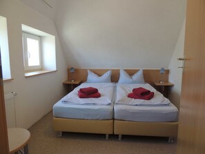 A twin room with two beds, a window, bedside tables, and a radiator.