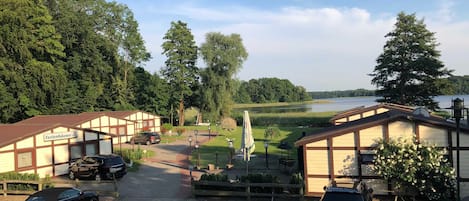 Ein Hotel mit einem Schotterweg, parkenden Autos und Blick auf einen See.