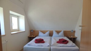 A twin room with two beds, a window, bedside tables, and a radiator.