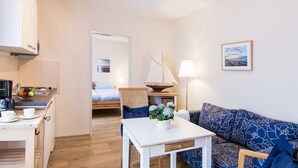A compact hotel room with a kitchenette, a dining area, a sofa, and a bed. - 2-room app. No. 2-3, 34 m², 1st floor, balcony - Gästehaus Schäfersruh (Scharbeutz)