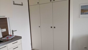 Una habitación con kitchenette, armario y un calendario en la pared.