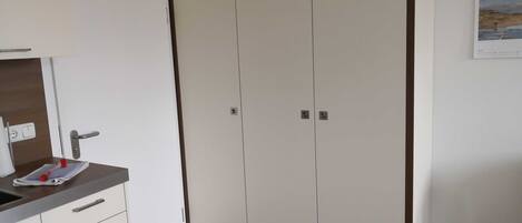 Ein Zimmer mit einer Küchenzeile, einem Kleiderschrank und einem Kalender an der Wand.