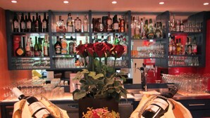 Una zona de bar con estantes llenos de botellas de licor, un arreglo floral central y dos cestas con servilletas.