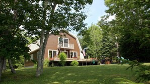 A two-story house with a balcony, surrounded by a well-maintained lawn and trees. - Pat's Place - Peacefull & charming cottage (Deer Isle)