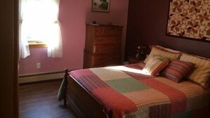 A bedroom with a bed, a dresser, a window with curtains, and a wall-mounted picture. - Pat's Place - Peacefull & charming cottage (Deer Isle)