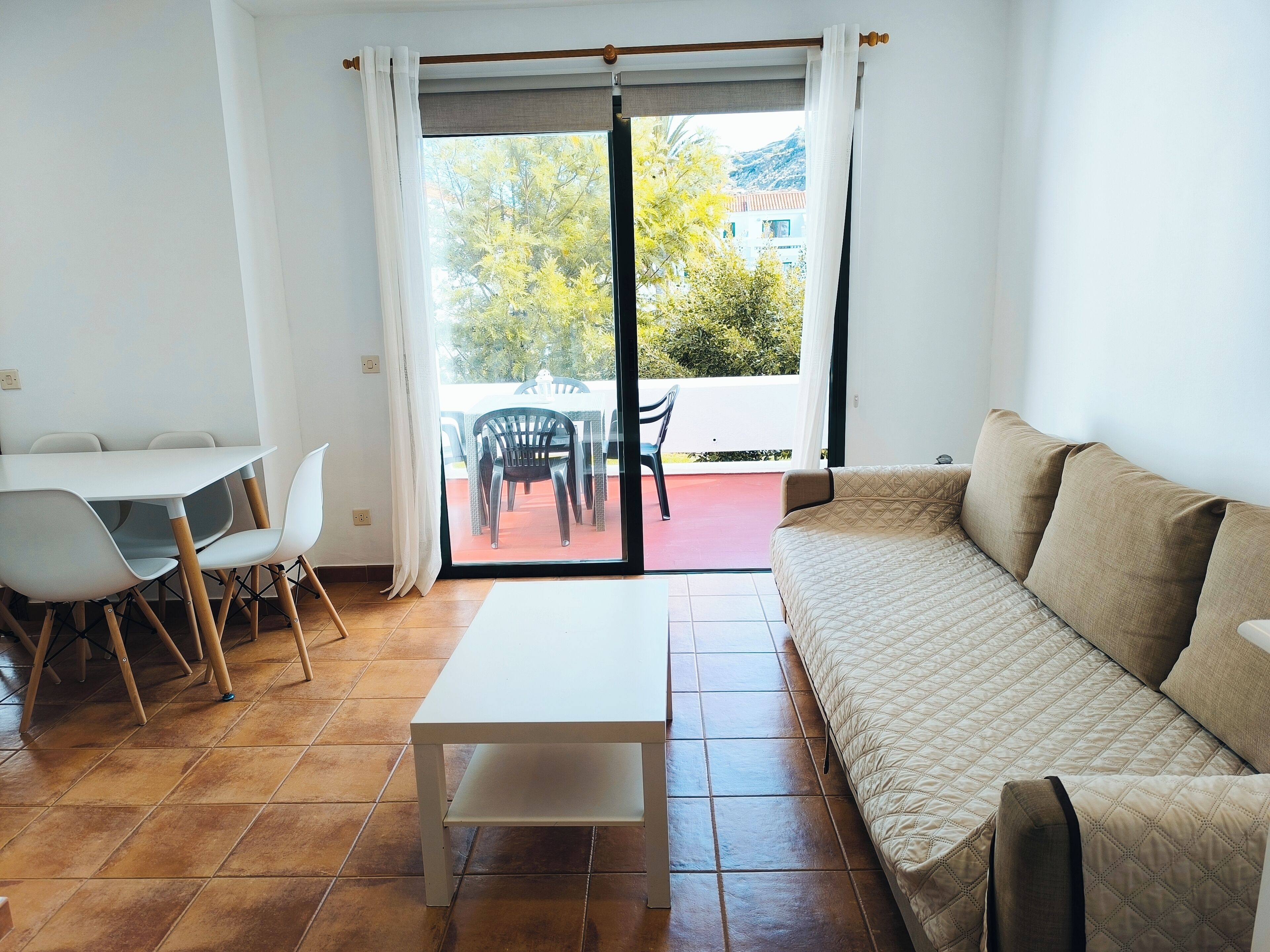 Ein Wohnzimmer mit einer Couch, einem Esstisch mit Stühlen und einer Glastür zu einer Terrasse.