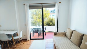 A living room with a sofa, a dining table with chairs, and a sliding glass door leading to an outdoor patio. - Amelia Cancajos: Comfort Swimming pool and beach nearby (Breña Baja)