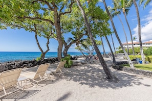 A beachside area with lounge chairs, a stone wall, and a view of the ocean. - POPULAR ON OCEAN COMPLEX - GREAT AMENITIES, DISCOUNTS AND LOCATION!!! (Kailua-Kona)