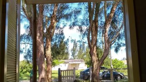 A covered outdoor area with a pathway leading to a house, surrounded by trees and a parked car. - Casa del Sol de Itapiruba (Itapiruba)