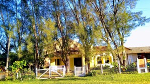 A yellow house with a tiled roof, surrounded by trees and a fenced yard. - Casa del Sol de Itapiruba (Itapiruba)