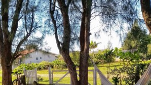 An outdoor seating area with a table and chairs, surrounded by trees and a hammock. - Casa del Sol de Itapiruba (Itapiruba)