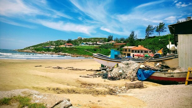 A beach with a boat, a wooden structure, and houses on a hillside. - Casa del Sol de Itapiruba (Itapiruba)