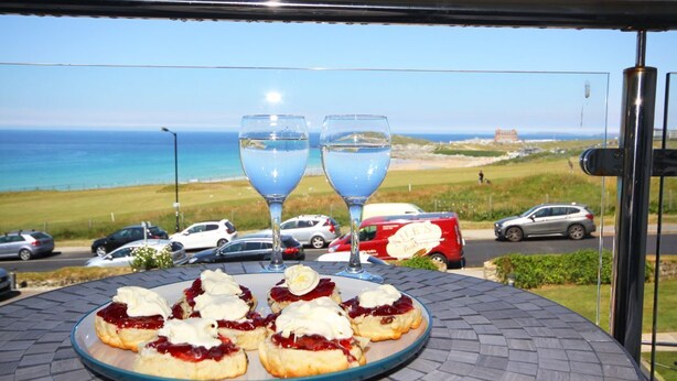 Una mesa con pasteles y dos vasos de agua, con vista a una playa y coches.