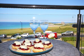 A table with pastries and two glasses of water, overlooking a beach and cars.