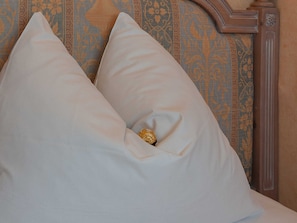Cama com duas almofadas e cabeceira decorativa.