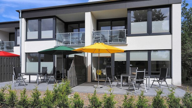 Ein zweistöckiges Gebäude mit Balkon und Terrassenbereich.