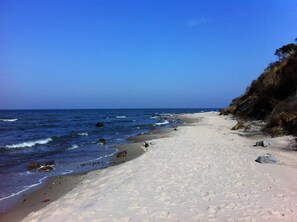 Une plage de sable fin, sous un ciel bleu azur et une mer calme.
