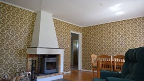 A living room with a fireplace, patterned wallpaper, and a green armchair. - Magnificent house with big garden (Munkfors)
