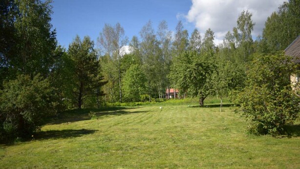 A grassy field with trees and a building in the background. - Magnificent house with big garden (Munkfors)