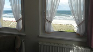 Una habitación con dos ventanas con vistas a una playa.