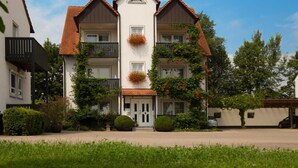 A two-story building with a symmetrical facade, a central entrance, and a balcony on the upper floor. - Vacation apartment - Kur & Golf Ferienwohnungen Wattenbach (Bad Windsheim)