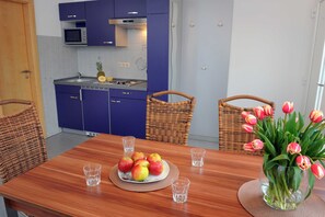 Un coin repas avec une table en bois, une assiette de pommes et un vase de tulipes.