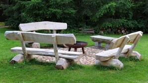Un espacio al aire libre rústico con un hogar de piedra y bancos hechos de troncos.