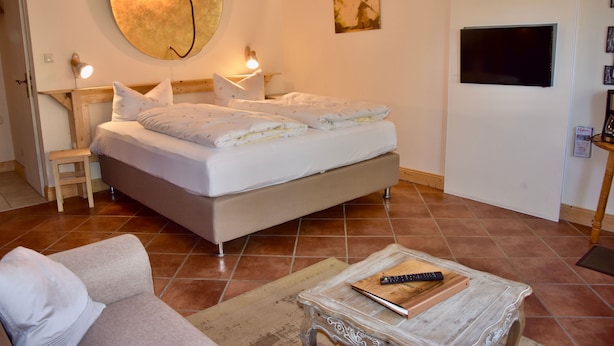 A bedroom with a bed, bedside tables, a TV, and a couch.