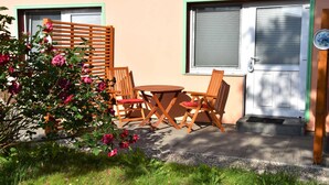 A patio with a wooden table and chairs, a wooden fence, and a door with a window.
