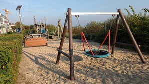 Een speeltuin met een schommel en een bandenschommel op zand.