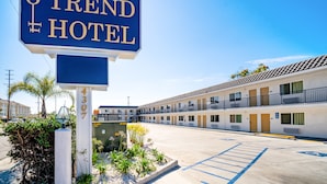 Un motel con un letrero que dice "TREND HOTEL" y un estacionamiento con el símbolo de estacionamiento para discapacitados.