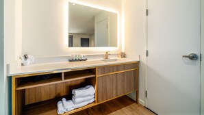 Un baño moderno con un tocador blanco, un espejo grande y un mueble de madera debajo.