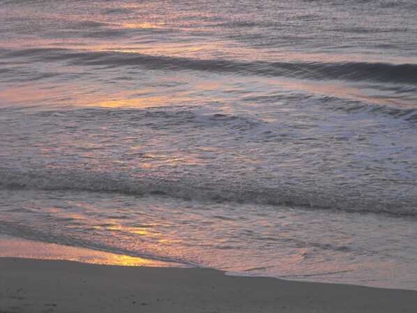 A beach with waves and a sunset.