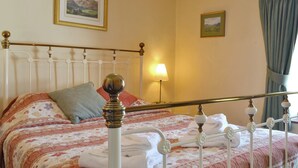 A neatly made bed with a patterned bedspread, a pillow, and folded towels. - 1 bedroom accommodation in Keswick (Keswick)