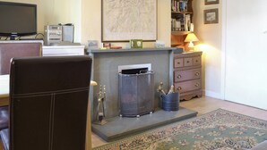 A living room with a fireplace, a television, a bookshelf, and a rug. - 1 bedroom accommodation in Keswick (Keswick)